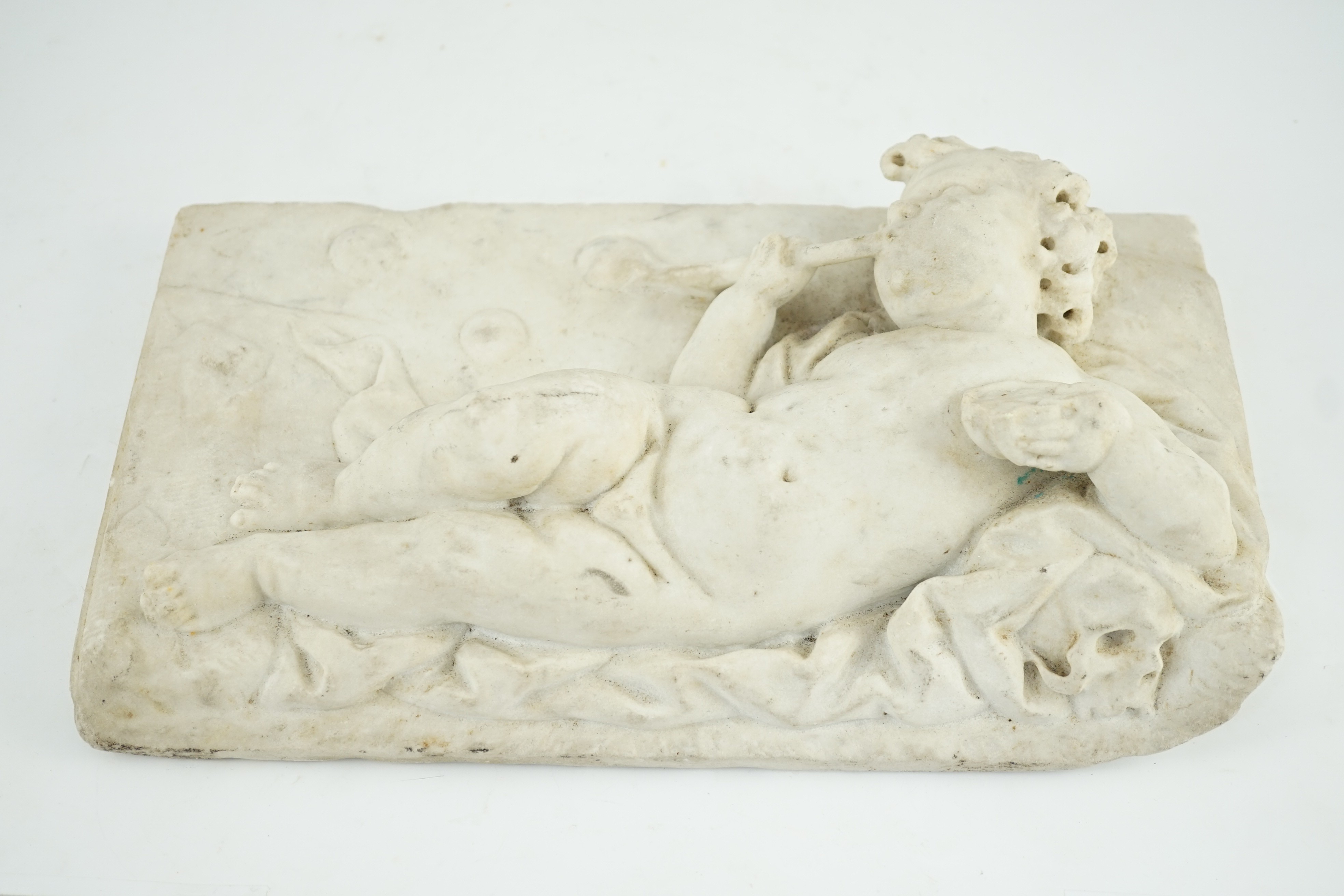 A 17th/18th century Italian marble plaque carved with a reclining cherub, 19.5 x 34.5cm